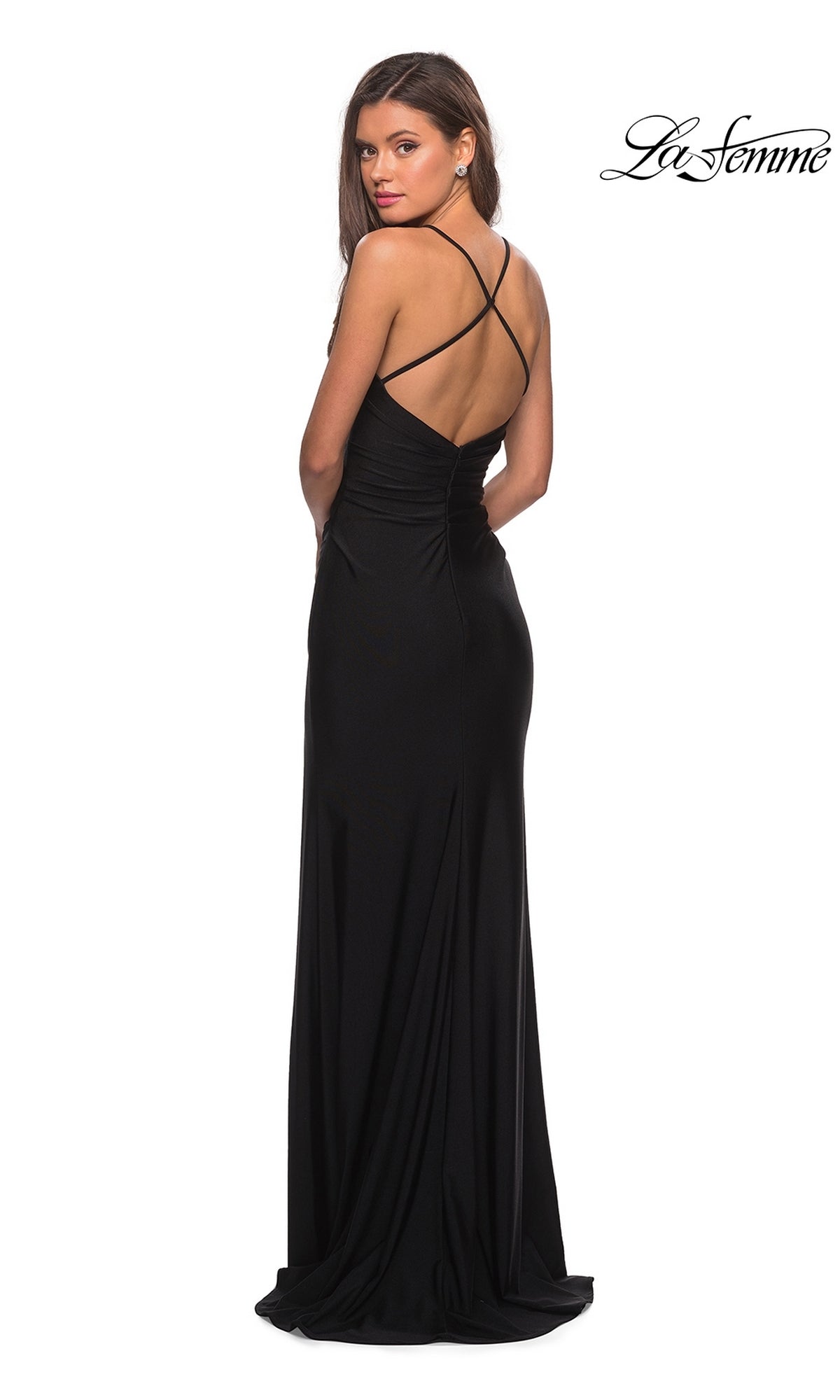 A woman stands against a white background, looking over her shoulder in the La Femme Open-Back Long V-Neck Prom Dress 28206, featuring crisscross straps and a classic black formal style.